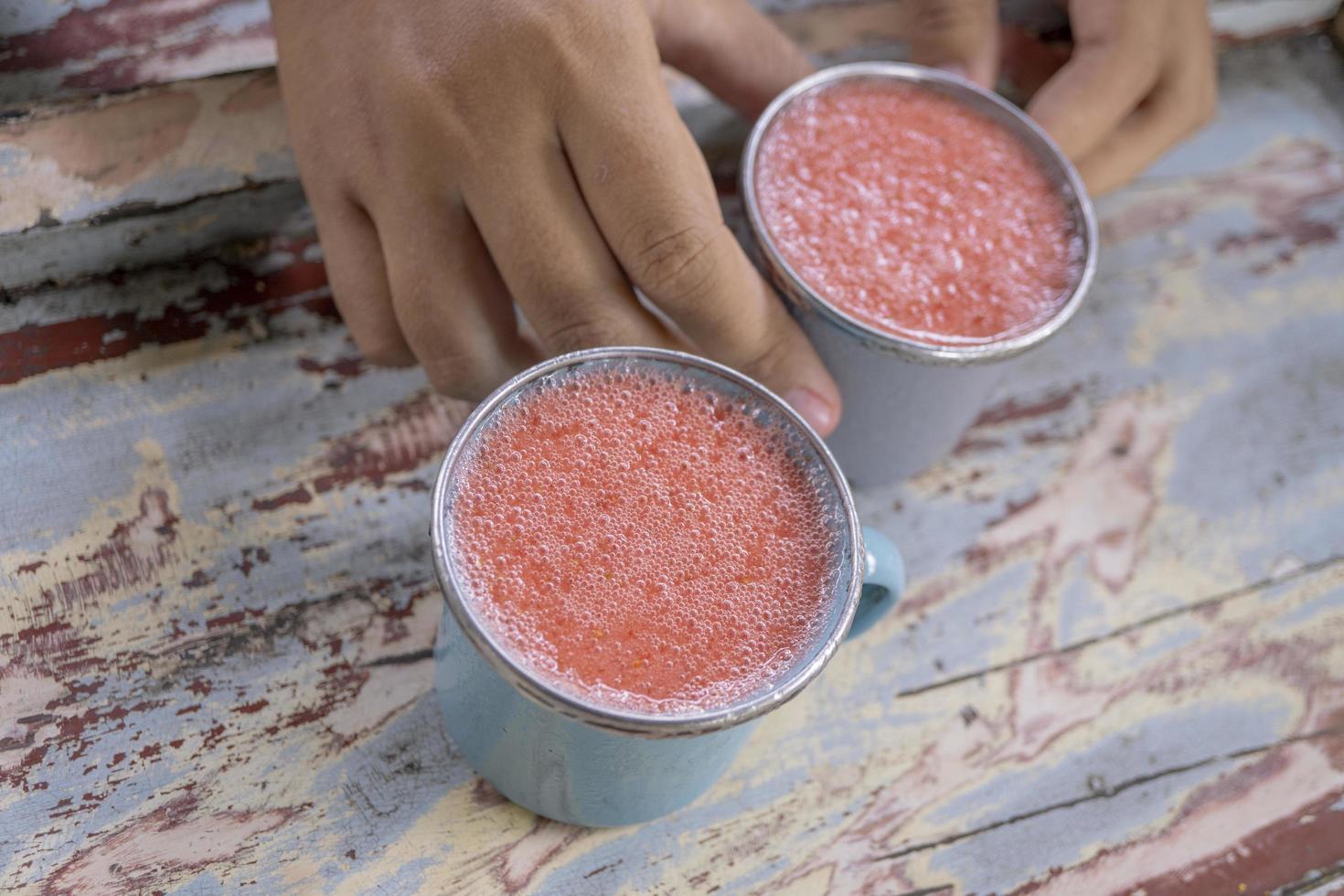 cerca arriba foto de Fresco fresa jugo en el azul taza a el jardín tienda. el foto es adecuado a utilizar para sano beber, menú fondo, y bebida contenido medios de comunicación.