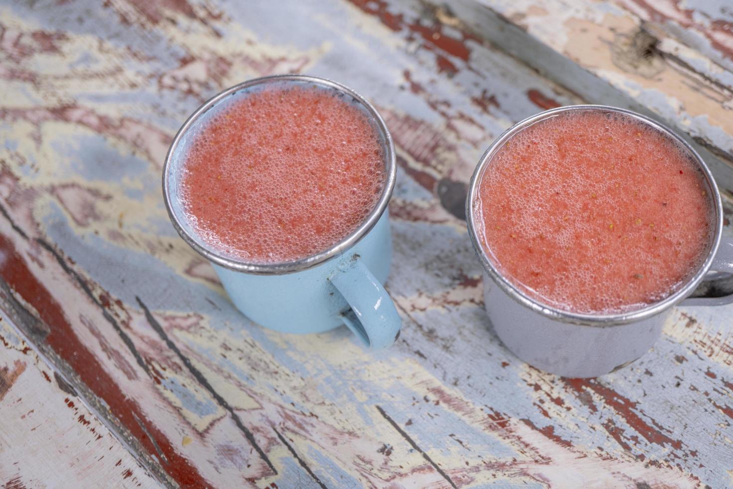 cerca arriba foto de Fresco fresa jugo en el azul taza a el jardín tienda. el foto es adecuado a utilizar para sano beber, menú fondo, y bebida contenido medios de comunicación.