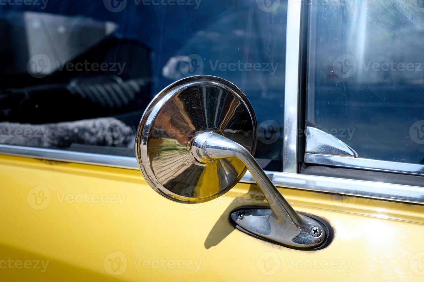 chromed rear view mirror of an old yellow car from the sixties photo