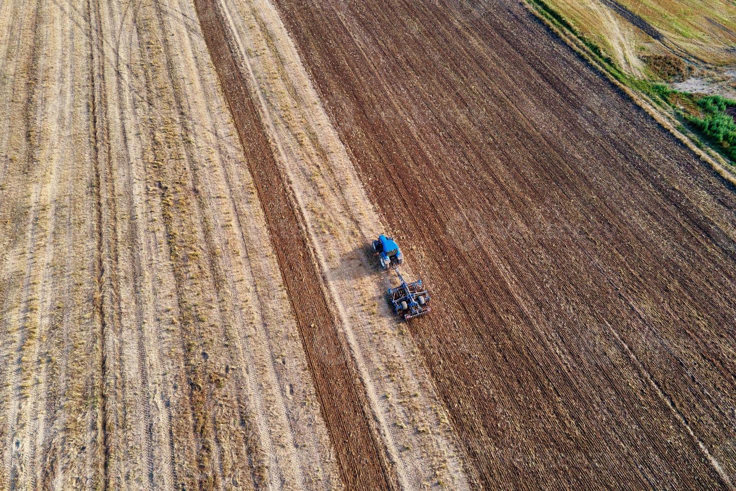 Tractor plows ground on cultivated farm field photo