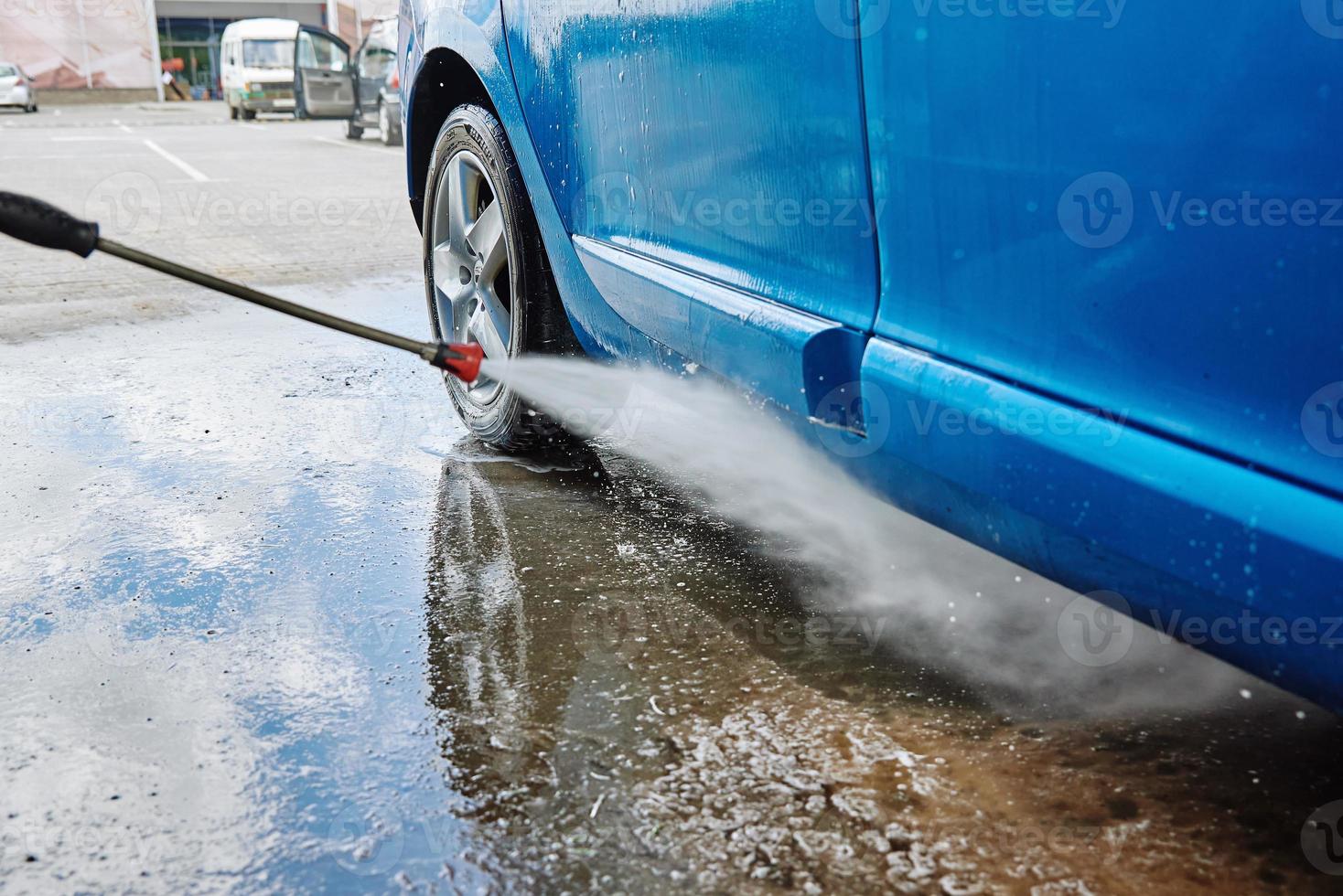 Cleaning car with high pressure water at car wash station photo