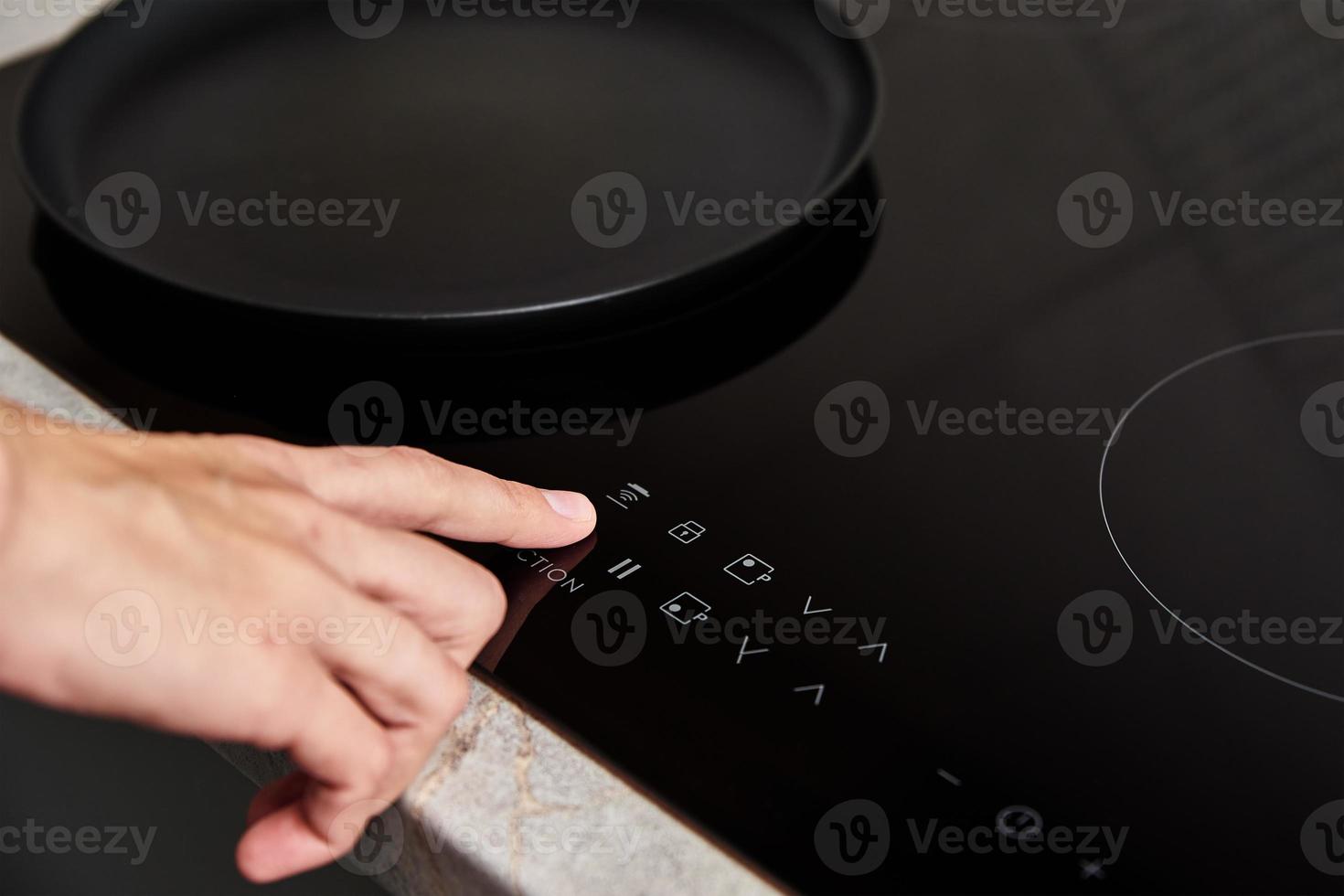 Woman hand turns on modern induction stove in the kitchen photo