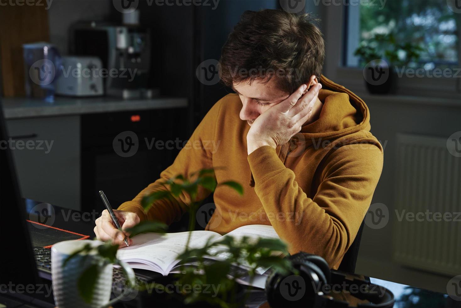 el hombre cansado trabaja hasta tarde en el lugar de trabajo por la noche foto