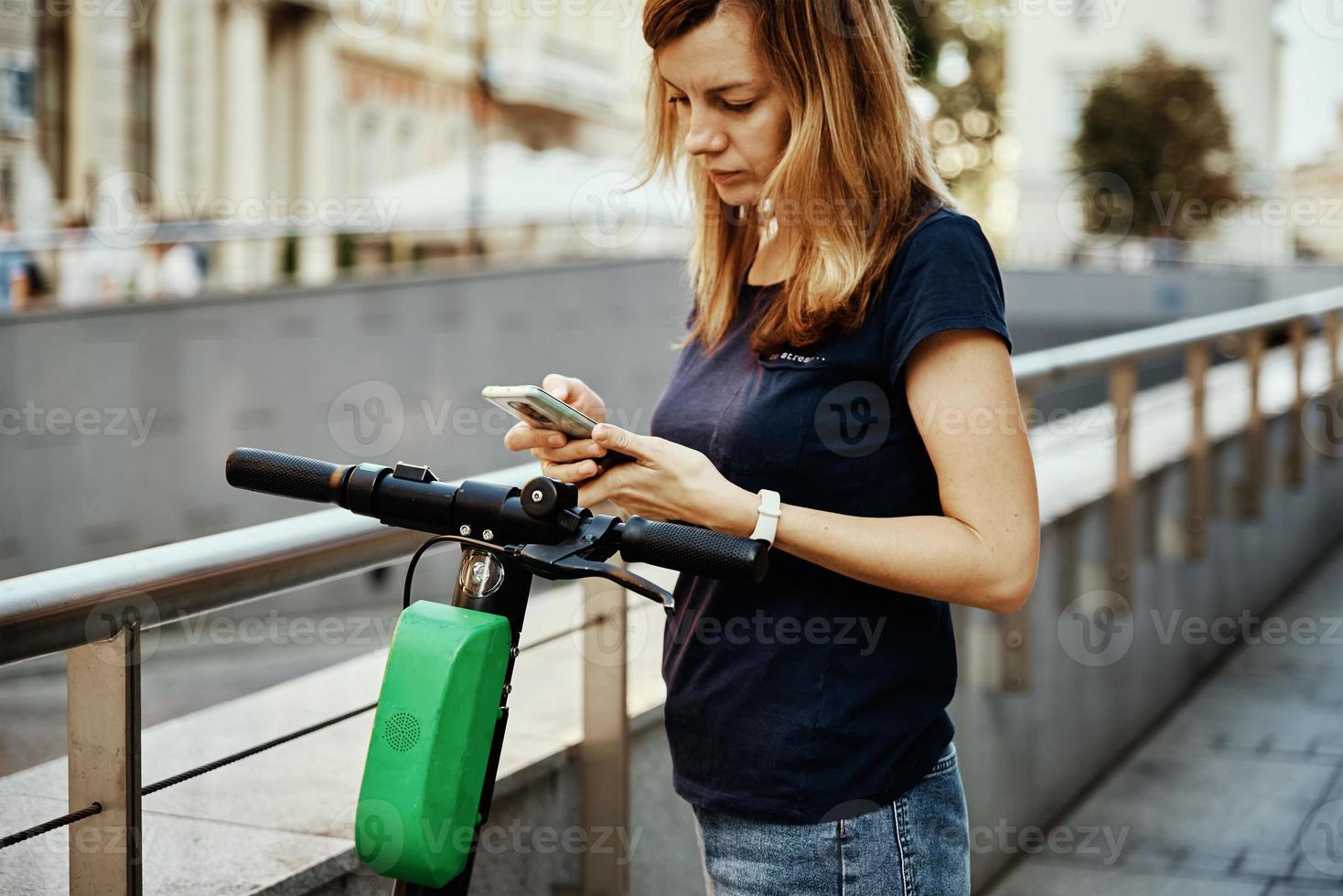 mujer desbloquear scooter eléctrico en alquiler con una aplicación de teléfono inteligente foto