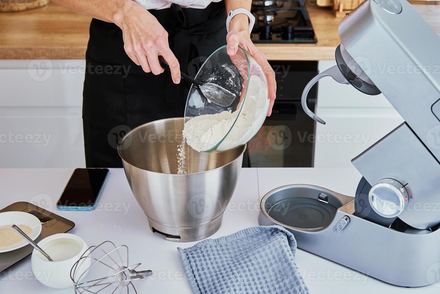 Woman cooking at kitchen and using kitchen machine photo