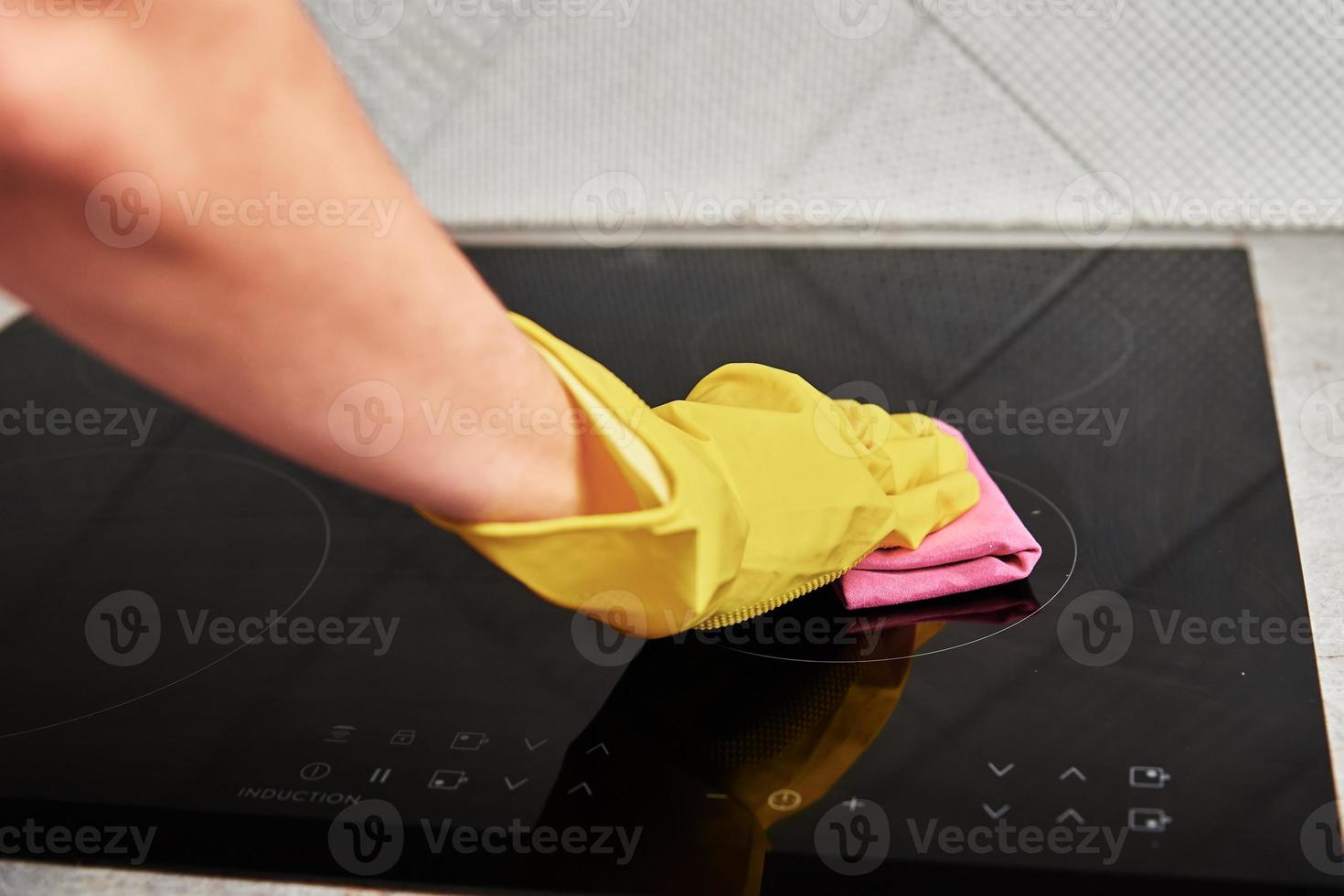 Woman in rubber gloves cleaning induction stove photo
