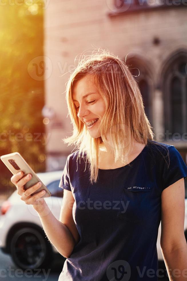 Woman with braces using smartphone at city street photo