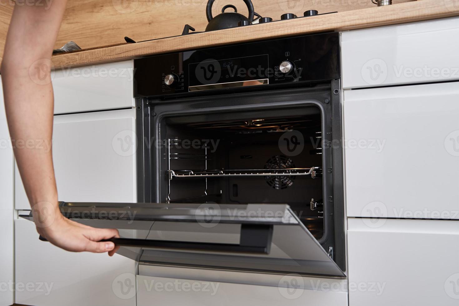 mujer abre la puerta del horno eléctrico foto