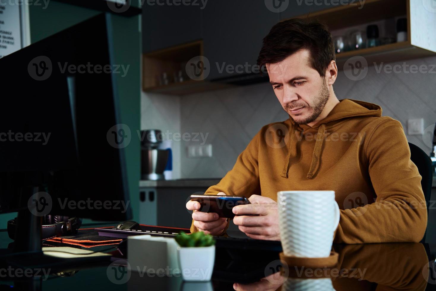 Man play game on smartphone while working at home warkplace photo