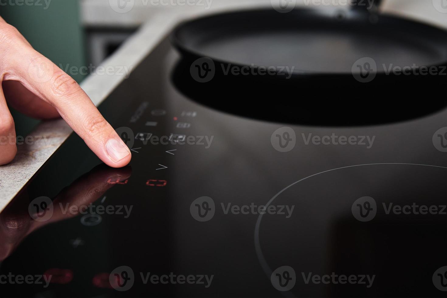 Woman hand turns on modern induction stove in the kitchen photo