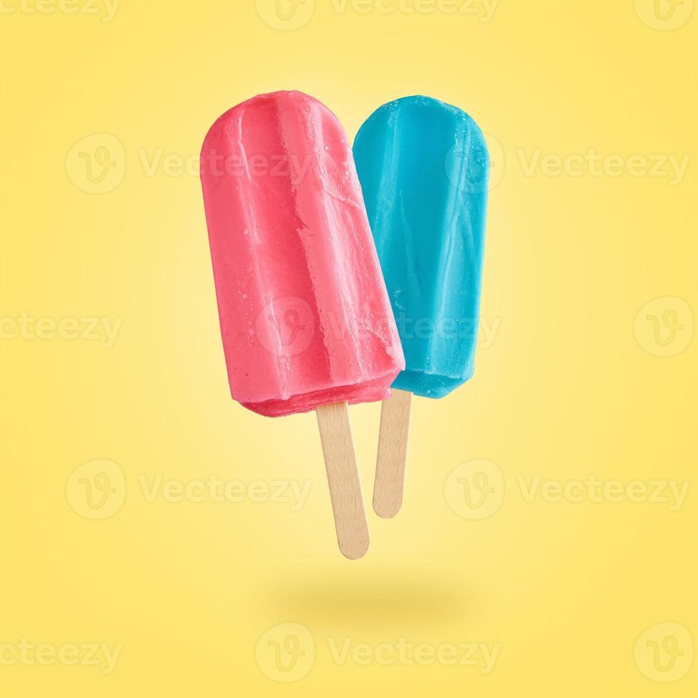 Two color popsicles on yellow background photo