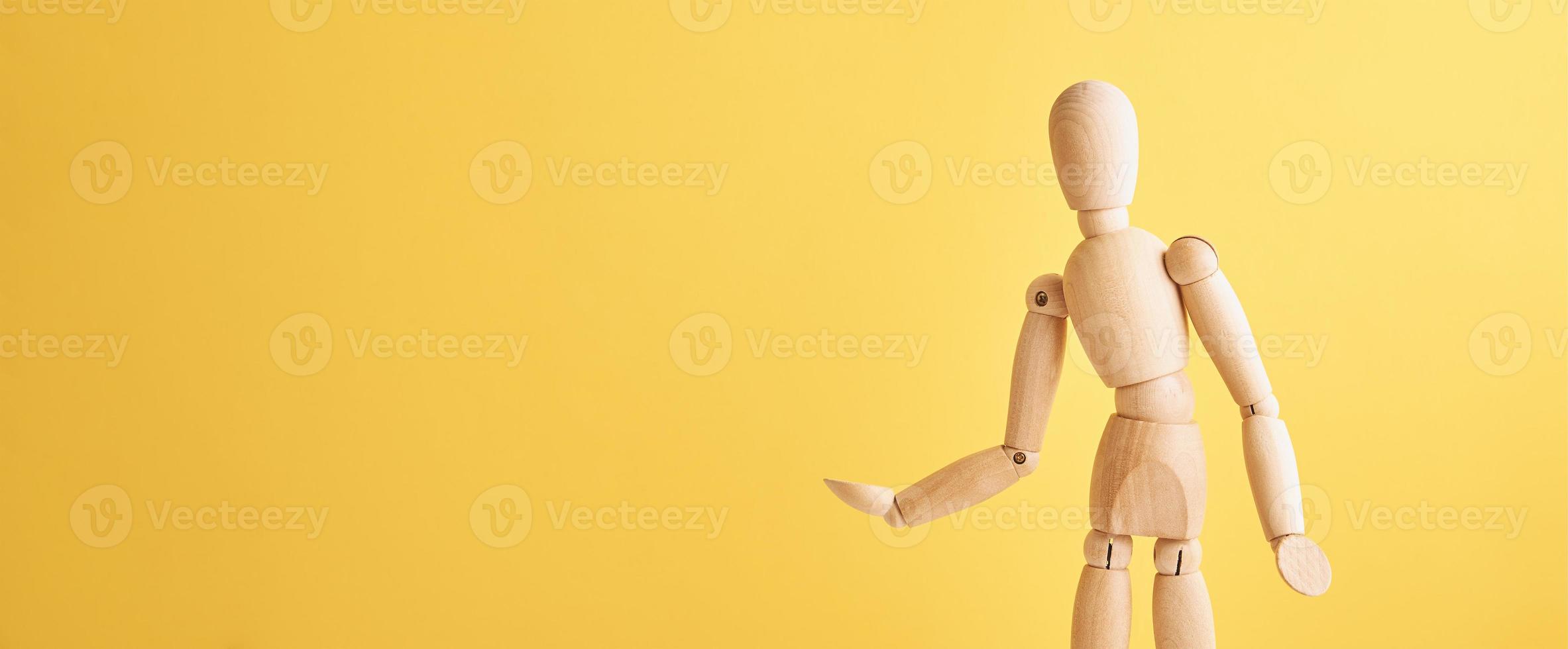 Wooden doll on yellow background photo