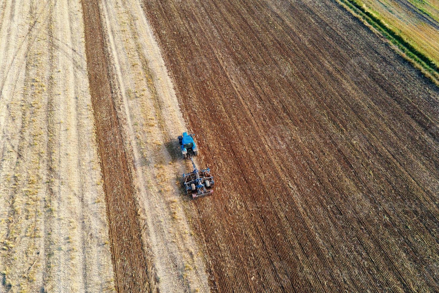 Tractor plows ground on cultivated farm field photo