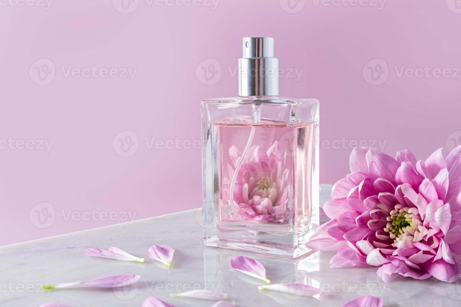 a transparent bottle of cosmetic spray or perfume against a beautiful lilac flowers. aroma presentation. pink background with a copy space. photo