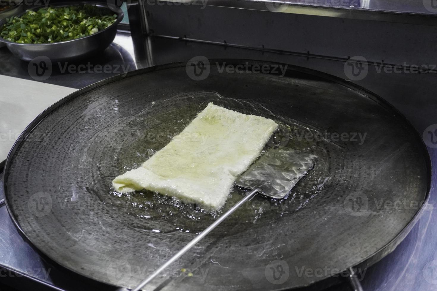 Frying Martabak Telor or omelet martabak in hot oil. Savoury pan-fried pastry stuffed with egg, meat, and spices. Traditional food snacks from Indonesia. photo
