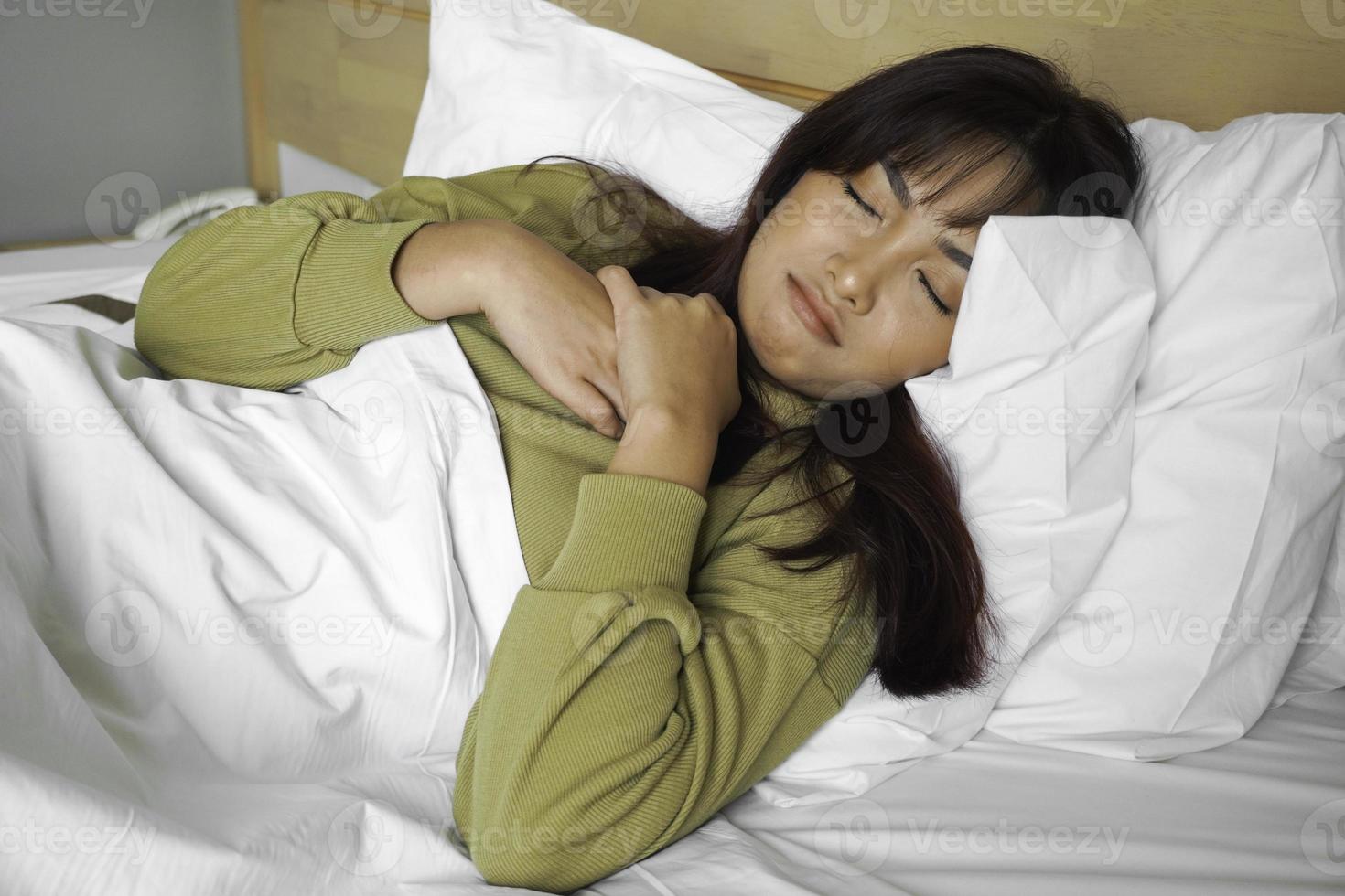 A sad young Asian woman is crying while lying on the bed photo