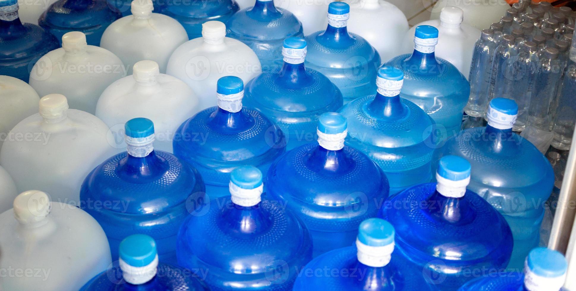 el galón de agua azul y el galón blanco que contiene agua potable han sido sellados con un sello de plástico en la planta de agua potable para esperar la entrega foto