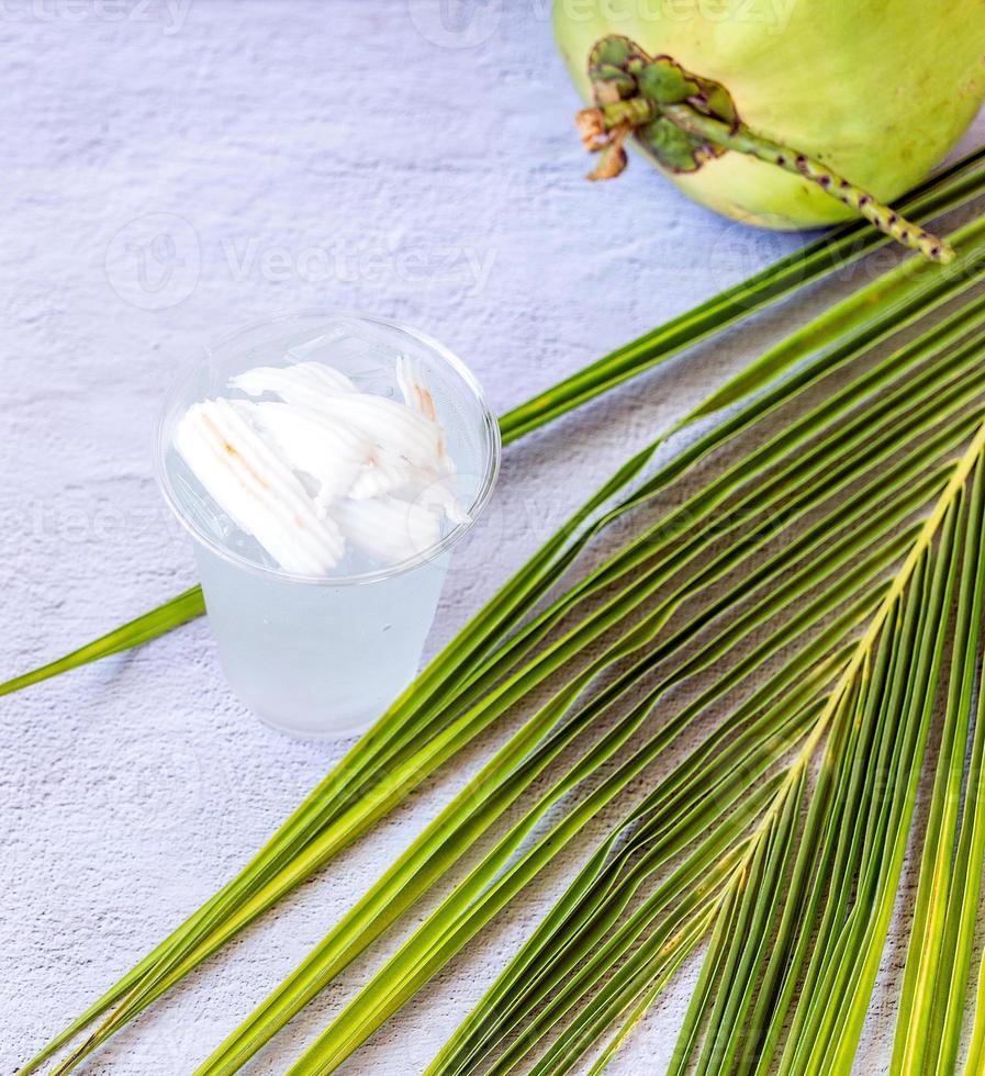 Ice coconut water drink in a plastic glass and coconut on white background photo