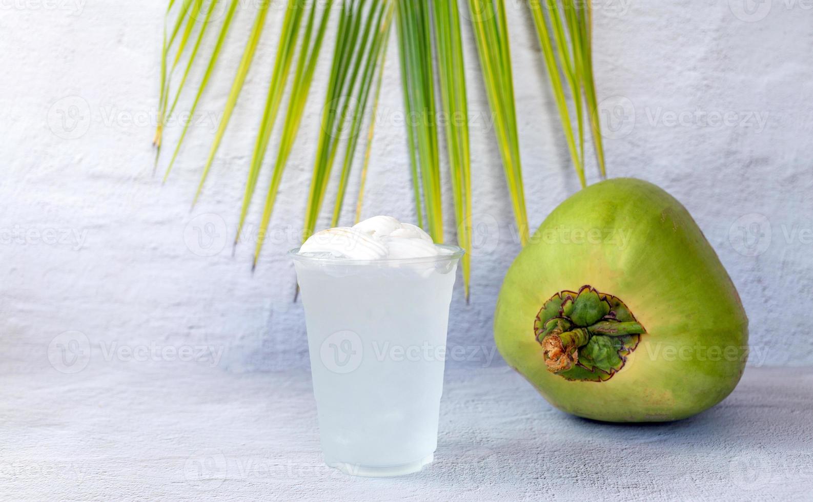 Ice coconut water drink in a plastic glass and coconut on white background photo