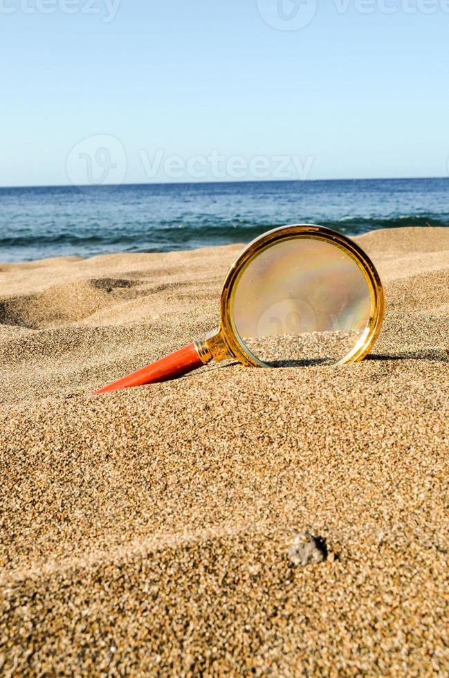 Magnifying glass in the sand photo