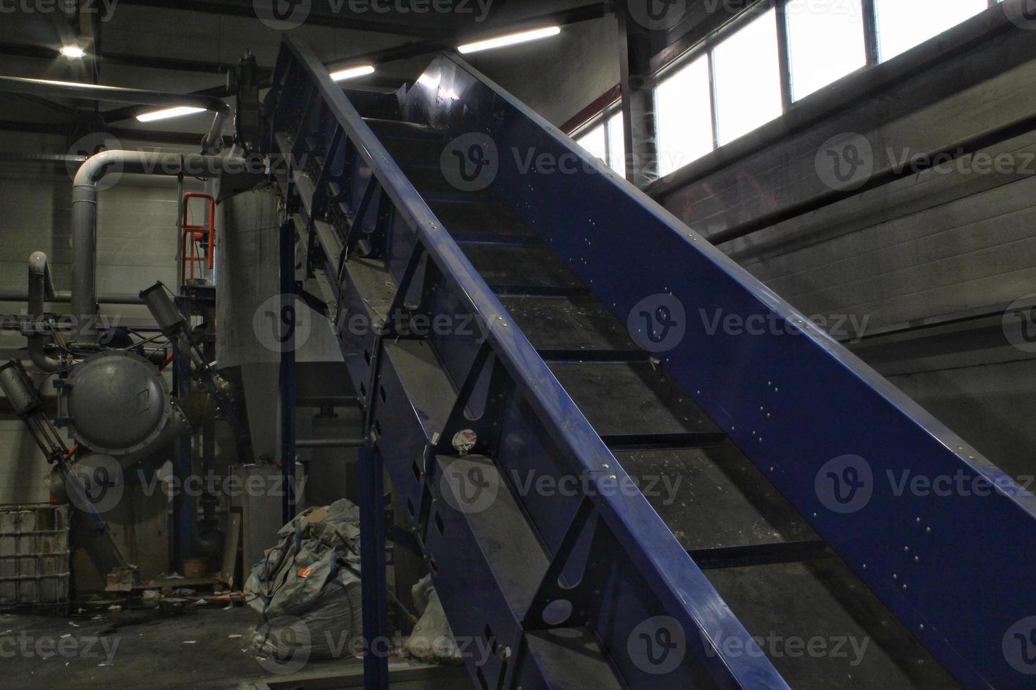 Shredding waste paper conveyor belt for recycling wrap, garbage and cardboard against bales of used carton boxes collected for reuse at industrial plant factory. Zero waste, eco-friendly concept photo