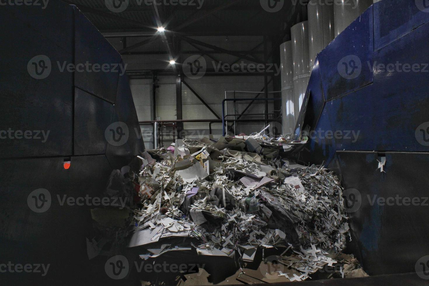 Shredding waste paper conveyor belt for recycling wrap, garbage and cardboard against bales of used carton boxes collected for reuse at industrial plant factory. Zero waste, eco-friendly concept photo