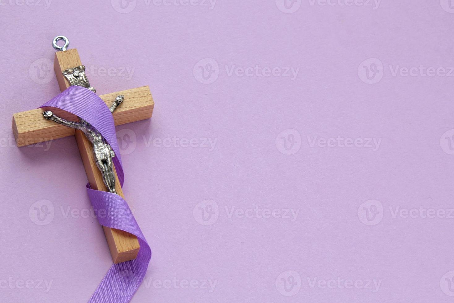 Christian religious wooden cross crucifix with violet ribbon on purple background. Catholic religion symbol. Good Friday, Lent Season, Palm Sunday, Ash Wednesday and Holy Week concept photo