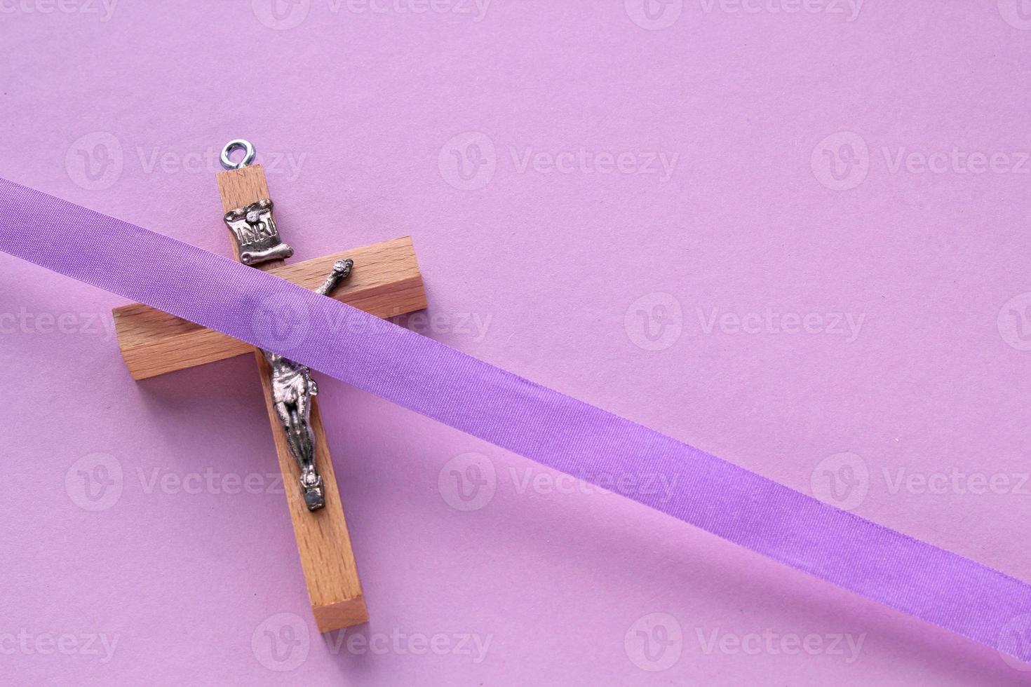 cristiano religioso de madera cruzar crucifijo con Violeta cinta en púrpura antecedentes. católico religión símbolo. bueno viernes, prestado estación, palma domingo, ceniza miércoles y santo semana concepto foto