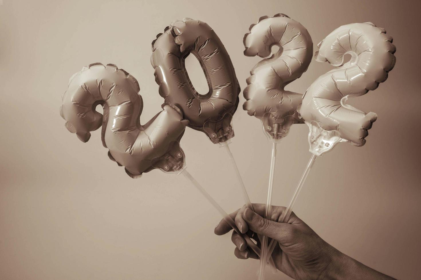 a woman's hand holds inflatable figures with numbers 2022, monochrome image photo