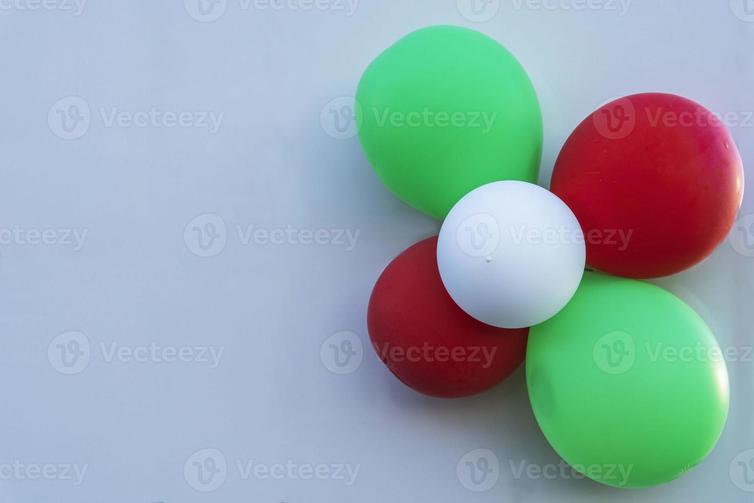 Colorful balloons on the light wall of the building, red, white and green balloons on a light background photo