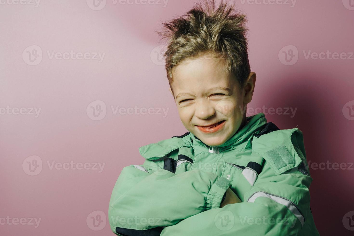 laughing disheveled European boy of five years in a winter green jacket photo