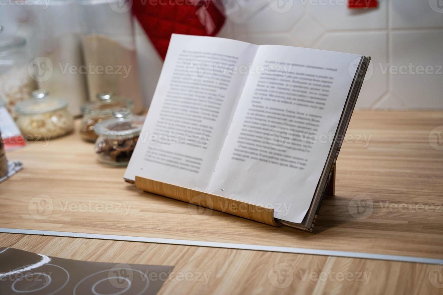 an open book in a stand on the kitchen table, storage jars, kitchen utensils photo