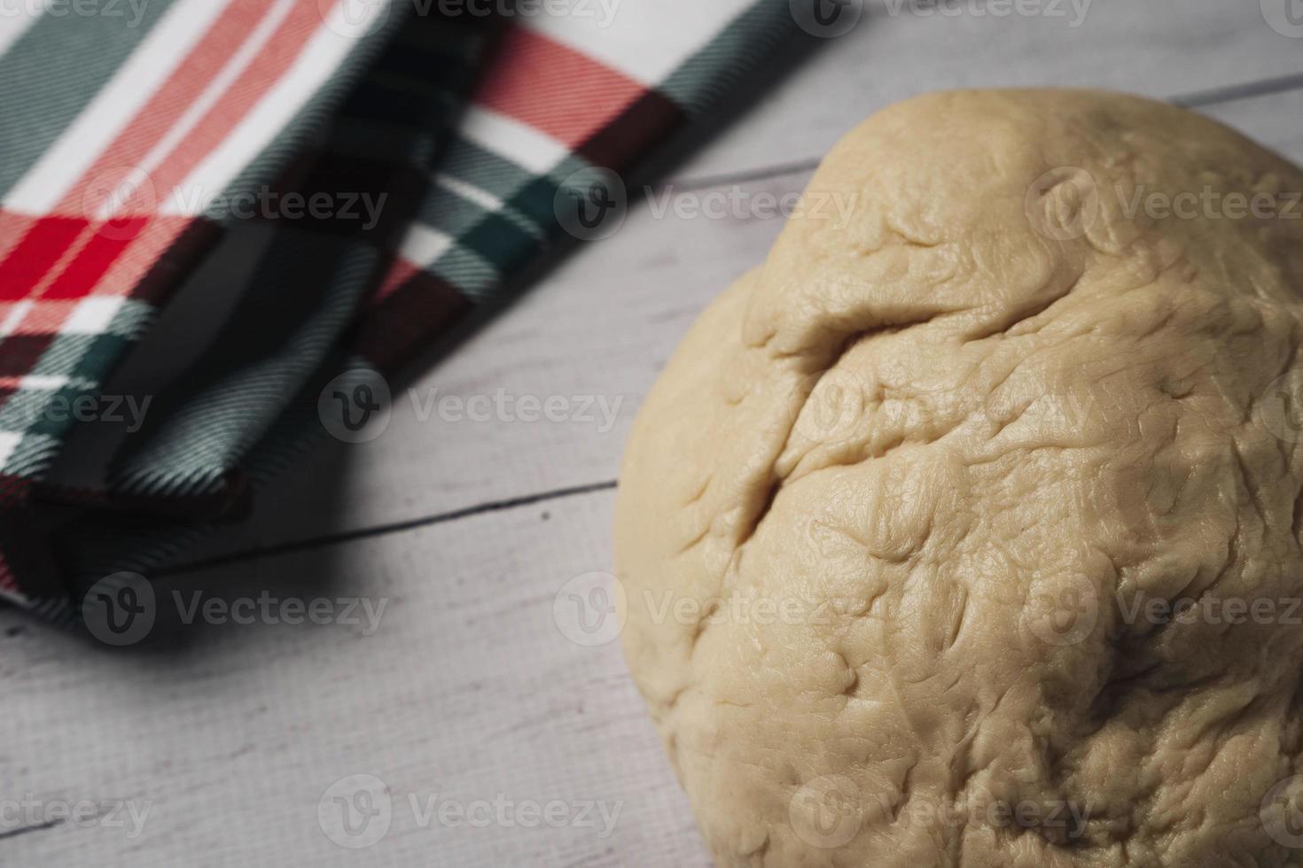 Fresco hecho en casa Pizza masa y un cocina toalla en el cocina mesa, un pelota de hecho en casa Pizza masa foto