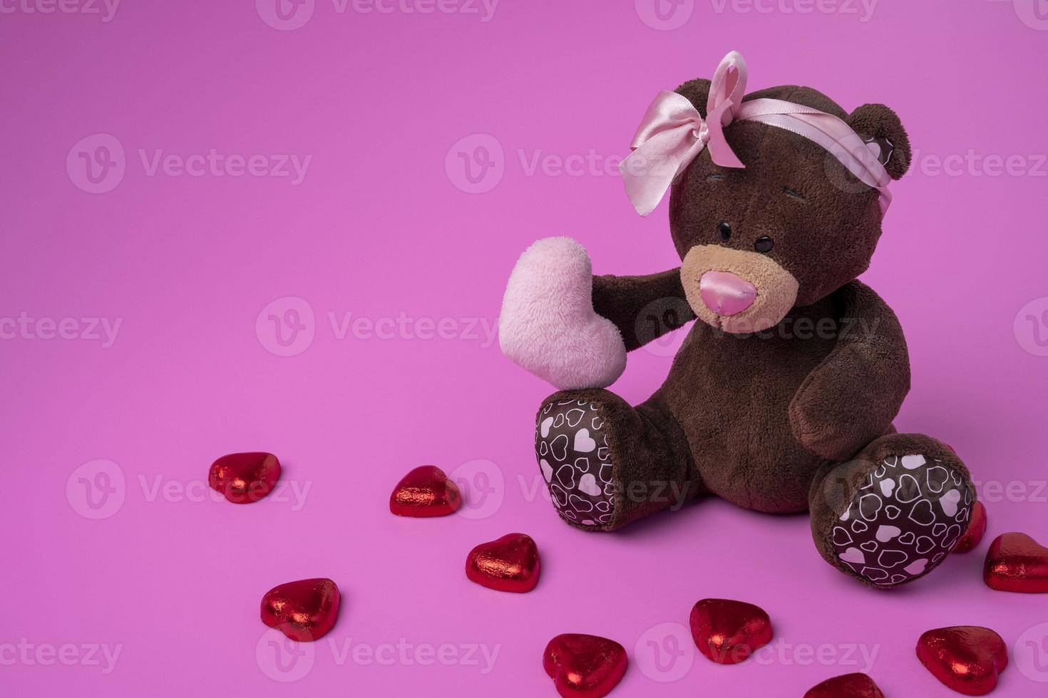 teddy bear teddy bear holds a fluffy heart in his paws. Pink background photo