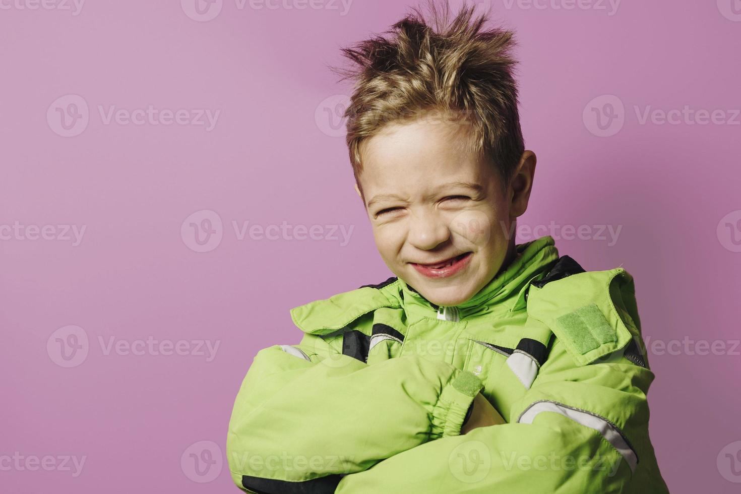 laughing disheveled European boy of five years in a winter green jacket photo