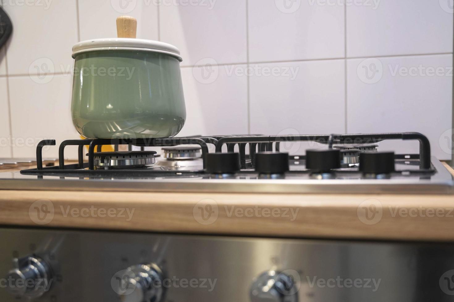 a light green saucepan with a lid stands on a home gas stove, home cooking photo