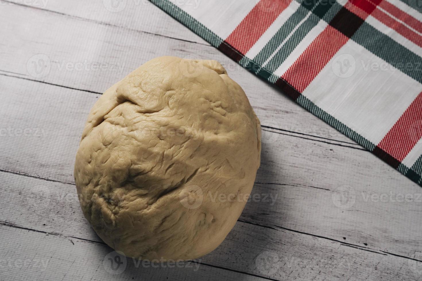 fresh homemade pizza dough and a kitchen towel on the kitchen table, a ball of homemade pizza dough photo