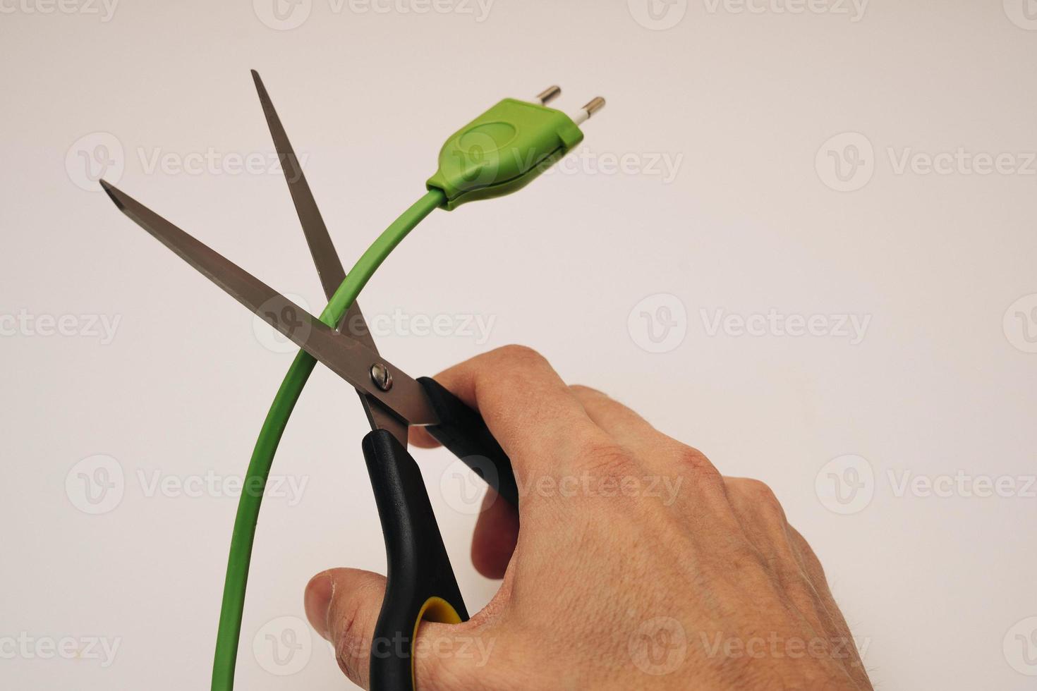a hand with office scissors cuts an electric wire, danger, violation, risk photo