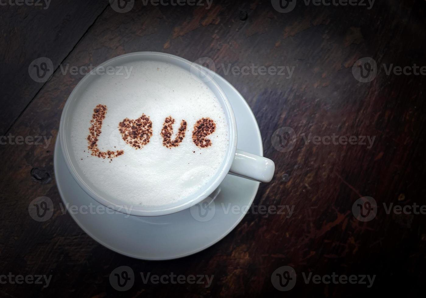 Hot fresh milk in a white cup topped with milk foam and sprinkled with chocolate in the letters LOVE.soft and selective focus. photo