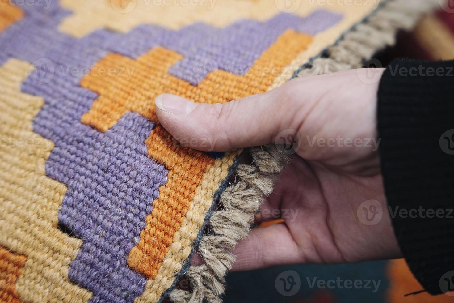 a woman's hand selects and touches a colored carpet in a store photo