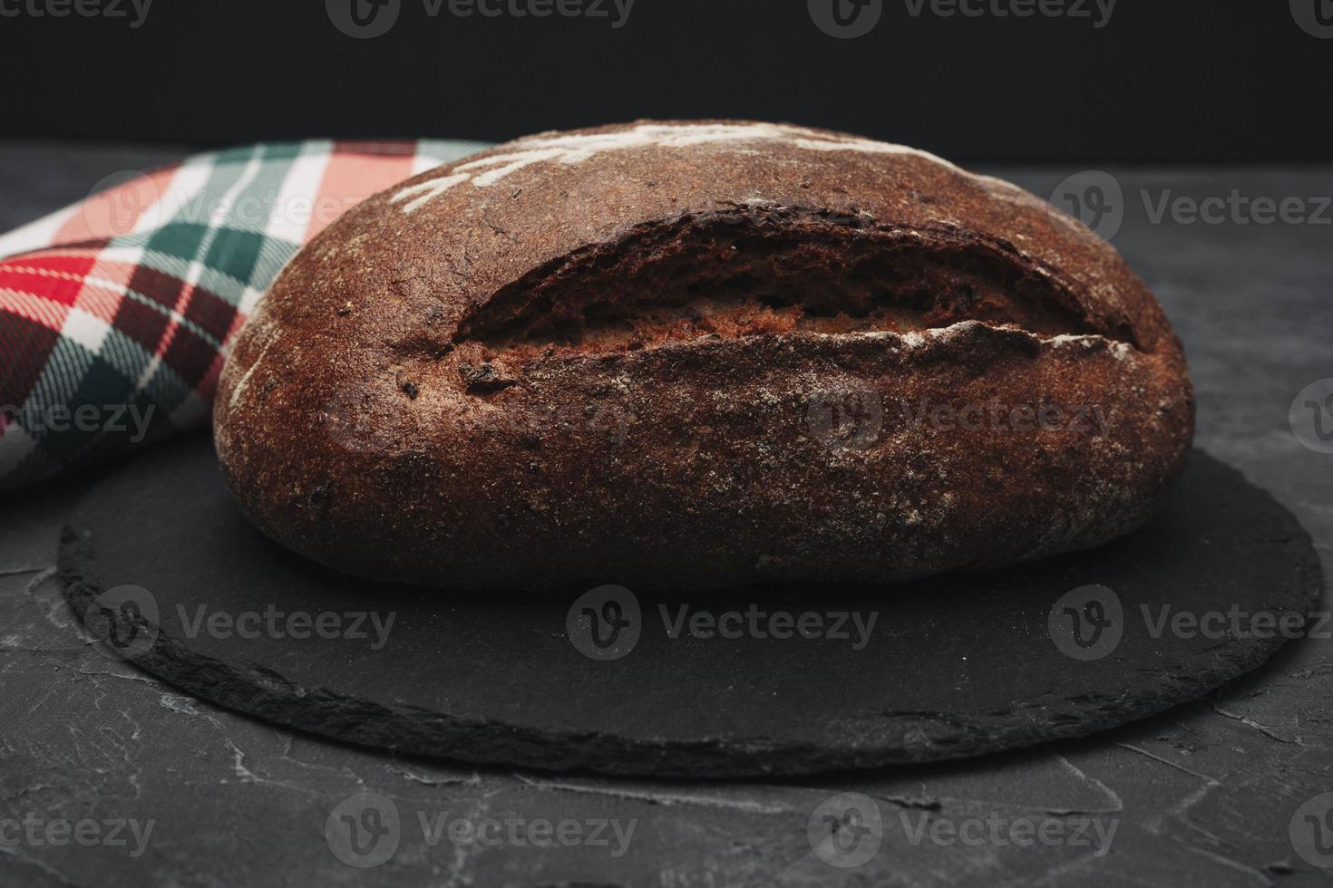 recién horneado calentar delicioso centeno redondo un pan de cerca y un cocina a cuadros toalla. el concepto de sano comiendo foto