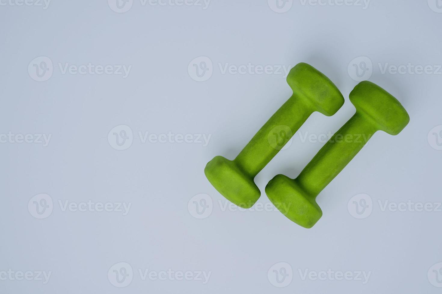 un par de ligero verde pequeño pesas en un blanco fondo, aptitud física, sano estilo de vida foto