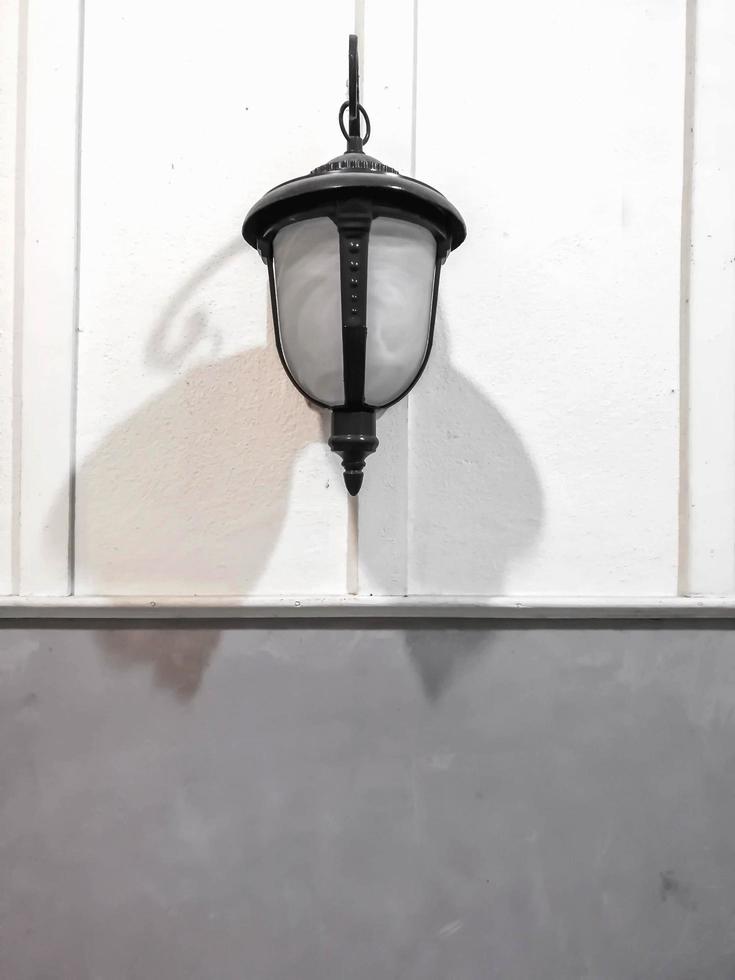 Ancient and vintage lamp hanging on white and mortar wall with shadow in a house. photo