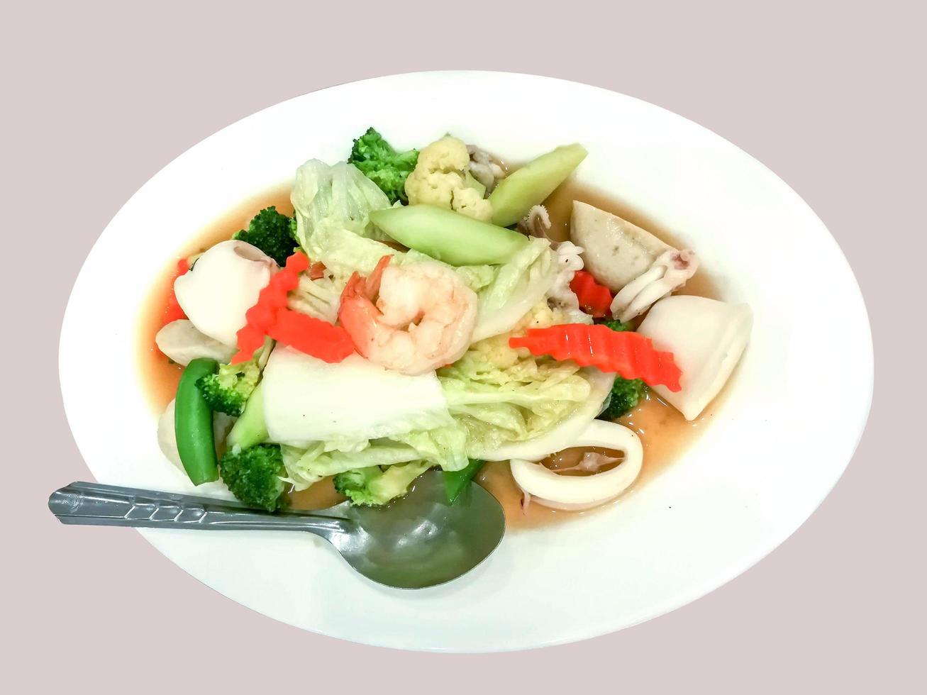 Top view Stir-fried vegetable with Seafood on white ceramic plate with stainless steel spoon on light gray background. photo