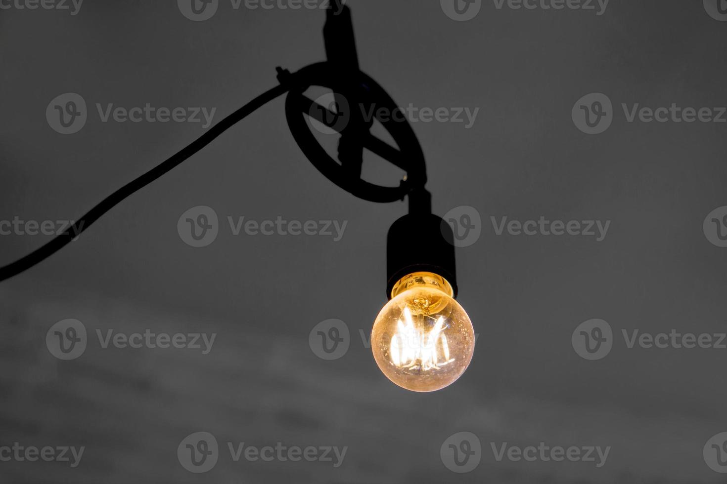 Closeup electric light bubs and switch on to yellow lights glowing on blurred ceiling background. photo