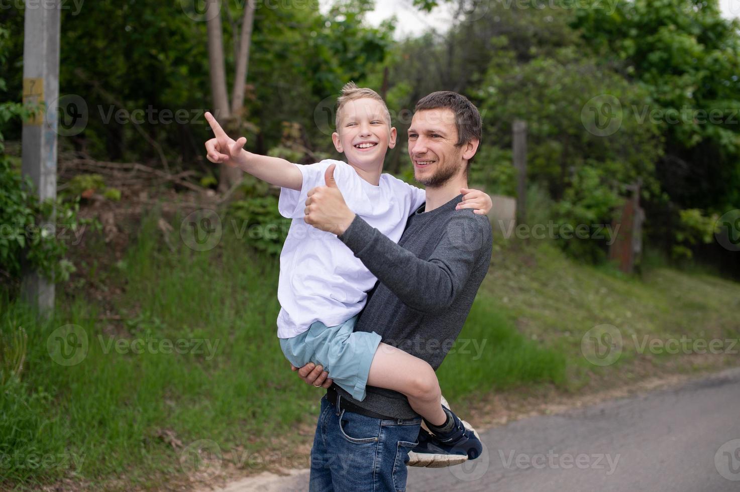 The boy is sitting in Dad's arms and they are laughing photo