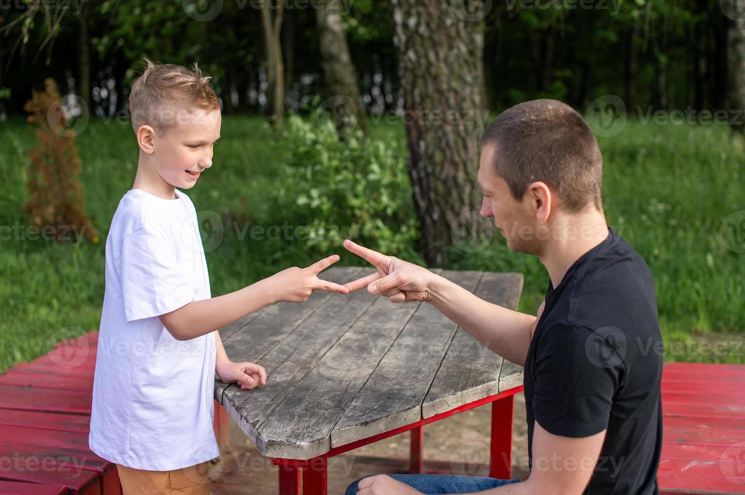 A cute boy is playing a game with his dad. shows signs with his hands photo
