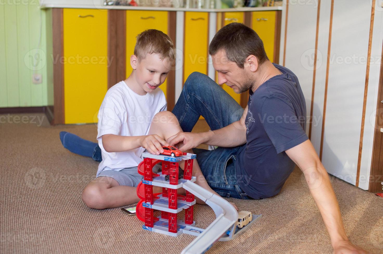 Cheerful dad plays with a cute boy at home in cars photo