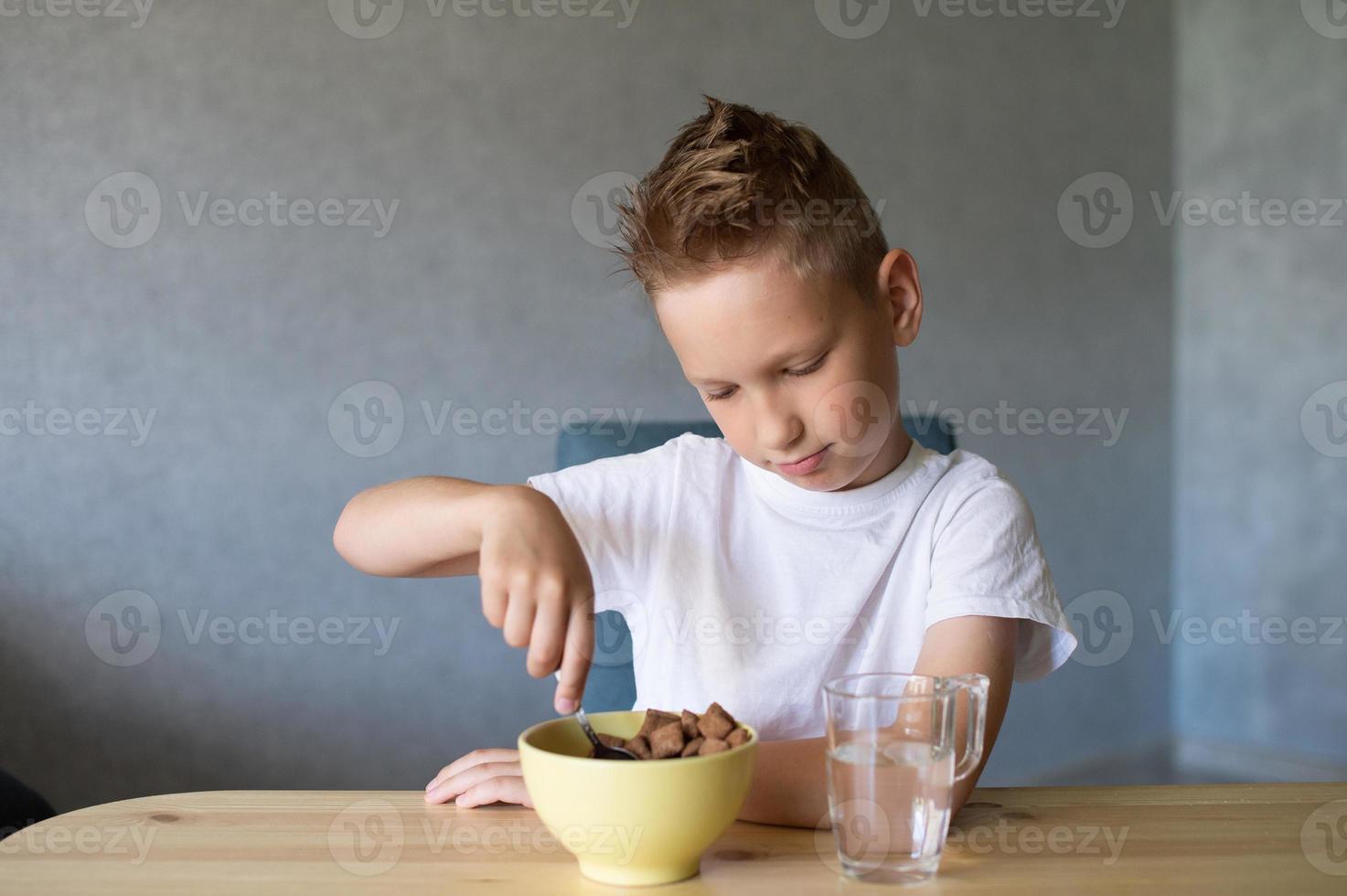 Cute boy eats a dry breakfast at home and smiles photo