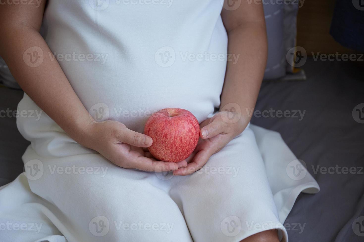 Young Asian Pregnant Woman using rattle toy to play with her unborn baby photo